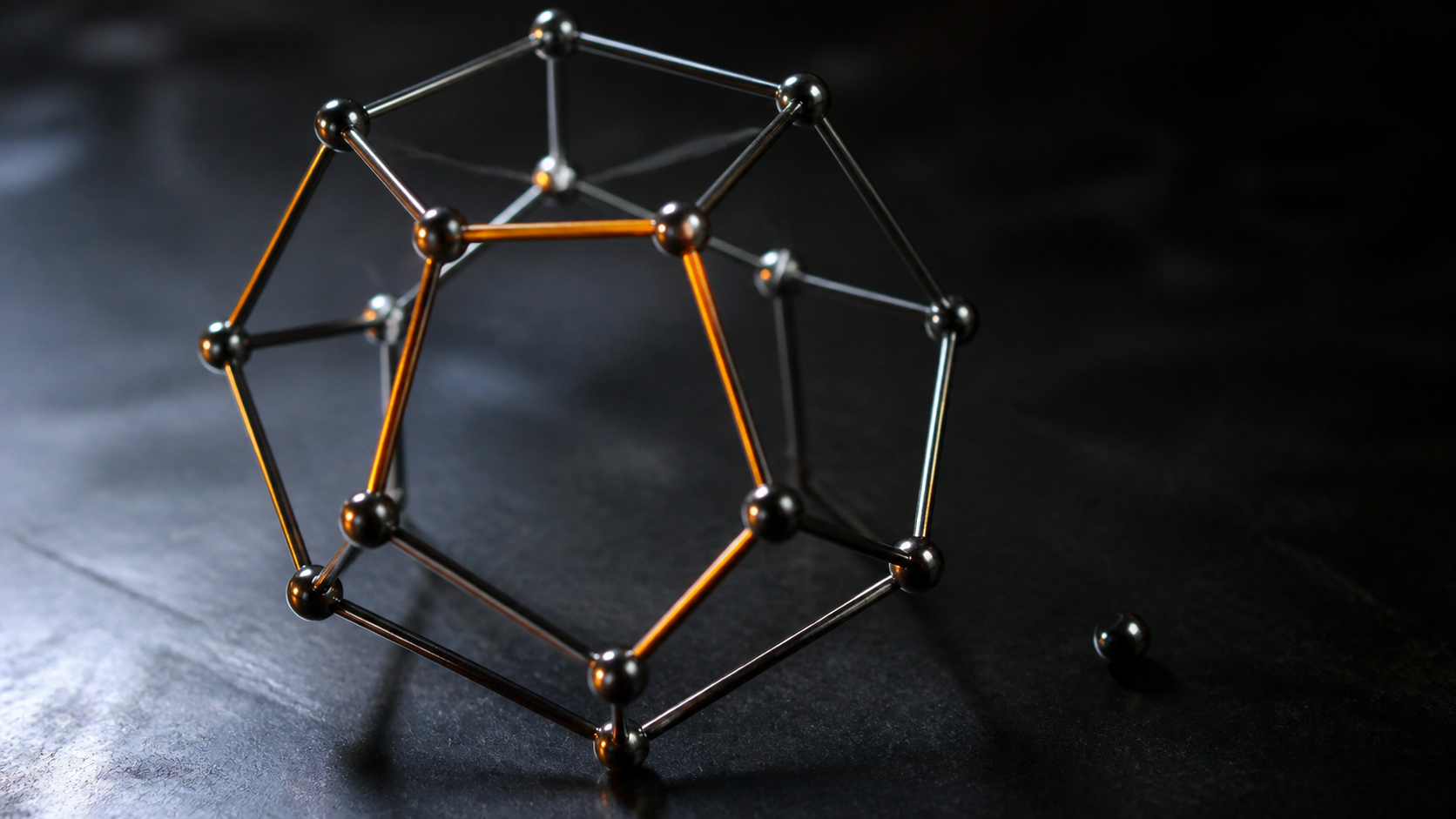 A metal geometric vacuum model assembled on a dark laboratory workbench